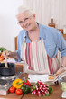 Elderly woman cooking with the help of a recipe