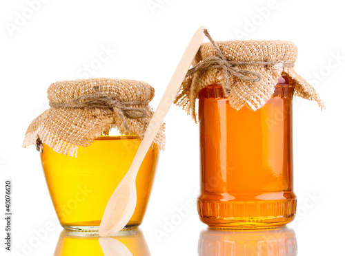 Photo: Sweet honey in jars with spoon isolated on white Sweet honey in jars with spoon isolated on white