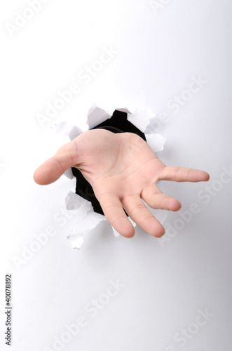 Photo: Hand through the hole in paper Hand through the hole in paper