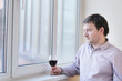 Middle age man with wine glass looking into the window
