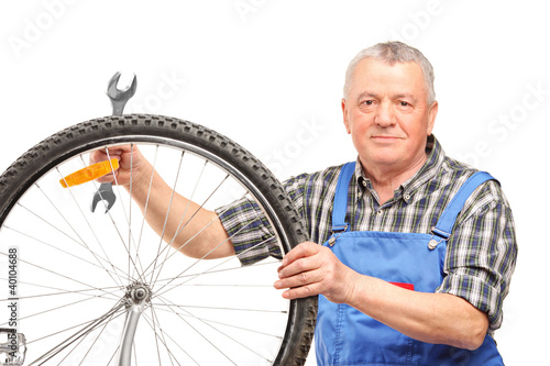 Photo: Middle aged man holding wrench and repairing bicycle wheel Middle aged man holding wrench and repairing bicycle wheel