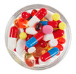 Pills, tablets and drugs heap in glass bowl isolated on white