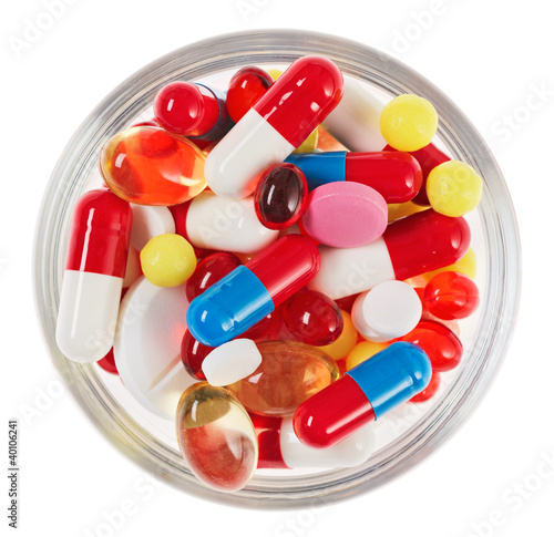 Photo: Pills, tablets and drugs heap in glass bowl isolated on white Pills, tablets and drugs heap in glass bowl isolated on white