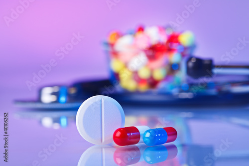 Photo: Pills and tablets macro still life on violet, medical therapeuti Pills and tablets macro still life on violet, medical therapeuti