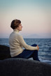 Foto: girl sitting on a rock by the sea at sunset girl sitting on a rock by the sea at sunset