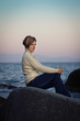 Foto: girl sitting on a rock by the sea at sunset girl sitting on a rock by the sea at sunset