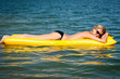 Details der Fotografie Summer woman floating on yellow water mattress