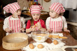 Foto: Three little chefs enjoying in the kitchen making big mess. Litt Three little chefs enjoying in the kitchen making big mess. Litt