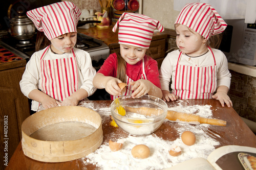Foto: Three little chefs enjoying in the kitchen making big mess. Litt Three little chefs enjoying in the kitchen making big mess. Litt