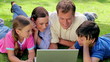 Smiling family lying together while looking at a laptop