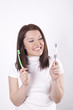 Young beautiful woman deciding which toothbrush to use