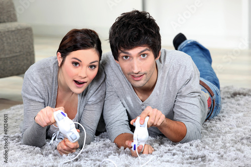 Foto: Couple laying on rug playing video games Couple laying on rug playing video games