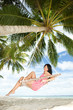 Happy woman relaxing in hammock on a tropical beach