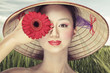 Beautiful vietnamese girl in a traditional hat is holding flower