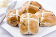 Sticky hot cross buns with rasins on white plate.