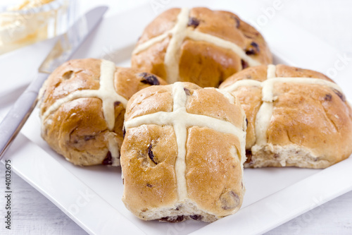Photo: Sticky hot cross buns with rasins on white plate. Sticky hot cross buns with rasins on white plate.