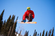 Snowboarder jumping through air with  blue sky in background