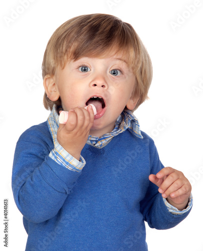 Photo: Beautiful baby with blue jersey eating a sweet Beautiful baby with blue jersey eating a sweet