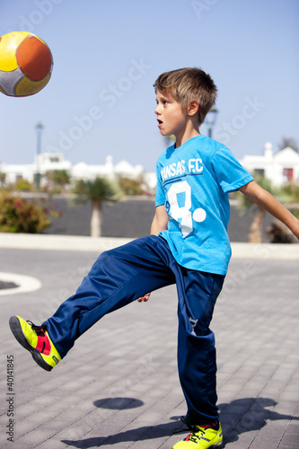 Photo: A boy playing football in the street A boy playing football in the street