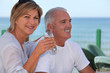 mature couple having fresh beer at cafe near sea