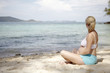 Foto: schwangere frau sitzt am strand schwangere frau sitzt am strand
