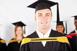 happy male college graduate with classmates at graduation