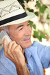 Man wearing a straw hat and talking on his mobile phone