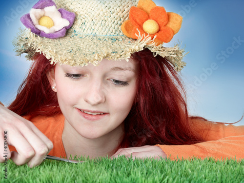 Foto: Teenager with flower hat cuts synthetic turf with nail scissors Teenager with flower hat cuts synthetic turf with nail scissors