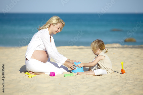 Foto: schwangere mutter spielt sand mit ihrer tochter schwangere mutter spielt sand mit ihrer tochter