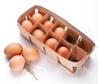 Eggs with a straw in a wooden basket on a white background.