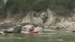 adult man on red canoe paddling for fun among rocks