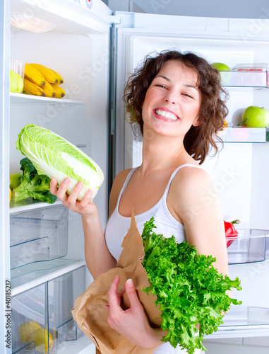 Photo: Beautiful Young Woman near the Refrigerator with healthy food Beautiful Young Woman near the Refrigerator with healthy food