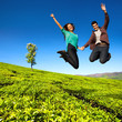 Jumping couple in green field.