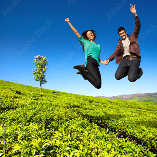 Photo: Jumping couple in green field. Jumping couple in green field.
