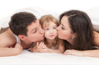 Foto: Happy family, mother, father and daughter on the white bed Happy family, mother, father and daughter on the white bed