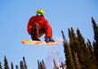 Snowboarder jumping through air with  blue sky in background