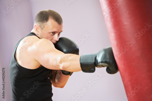 Photo: boxer man at boxing training with heavy bag boxer man at boxing training with heavy bag
