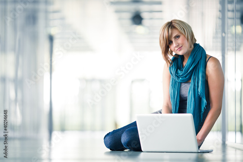 Photo: Pretty young female student with a laptop computer on college/un Pretty young female student with a laptop computer on college/un