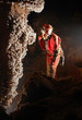 Beautiful stalactites in a cave with a speleologist