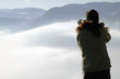 Woman photographing above clouds
