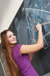 Pretty young college student writing on the chalkboard/blackboar