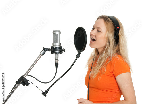 Photo: Girl in orange t-shirt singing with studio microphone Girl in orange t-shirt singing with studio microphone