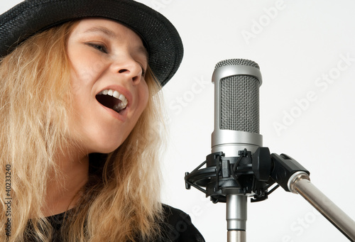 Photo: Young woman singing with studio microphone Young woman singing with studio microphone