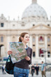 Pretty young female tourist studying a map at St. Peter's square