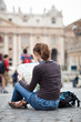 Pretty young female tourist studying a map at St. Peter's square