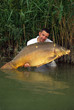Happy  fisherman holding a giant mirror carp