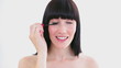Happy woman applying mascara on her eyelashes