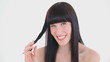 Dark-haired woman holding a strand of her hair