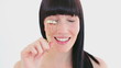 Smiling brunette using a curler for her eyelashes
