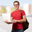 portrait of young man holding laptop and wearing backpack at cit